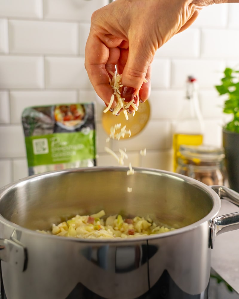 Dieses Bild zeigt wie der Käse zum Reis gegeben wird.