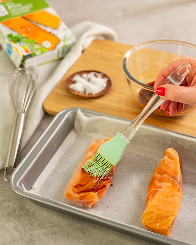 Dieses Bild zeigt wie der Lachs mit der Marinade bepinselt wird.