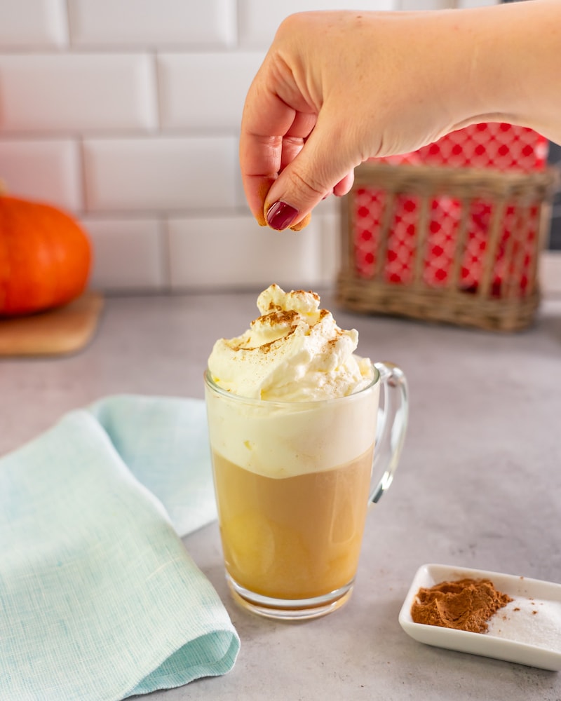 Dieses Bild zeigt wie der Zimt auf den Pumpkin Spice Latte gegeben wird.