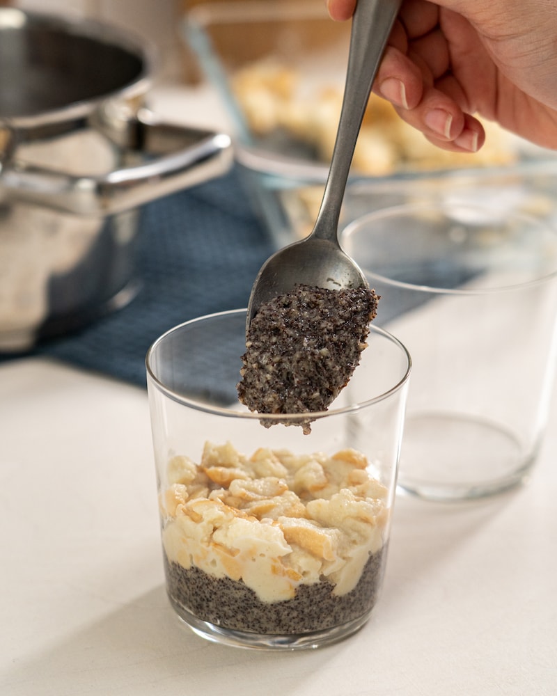 Auf diesem Bild siehst du wie das Mohn-Gemisch und die Milchbrötchen in ein Dessert-Glas geschichtet werden.