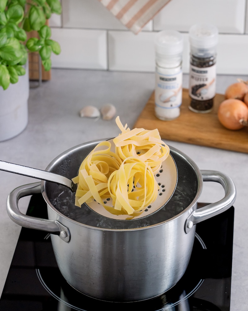 Diese Bild zeigt wie die Nudeln in das kochende Wasser gegeben wird.