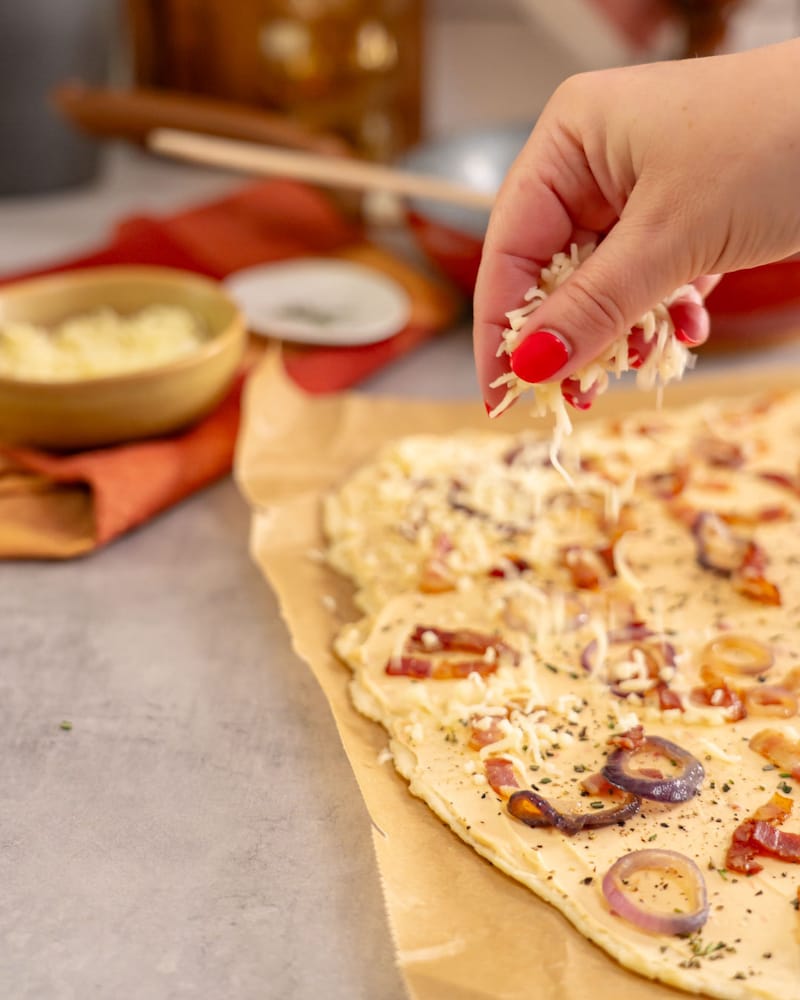 Dieses Bild zeigt wie der Teig mit Käse bestreut wird.