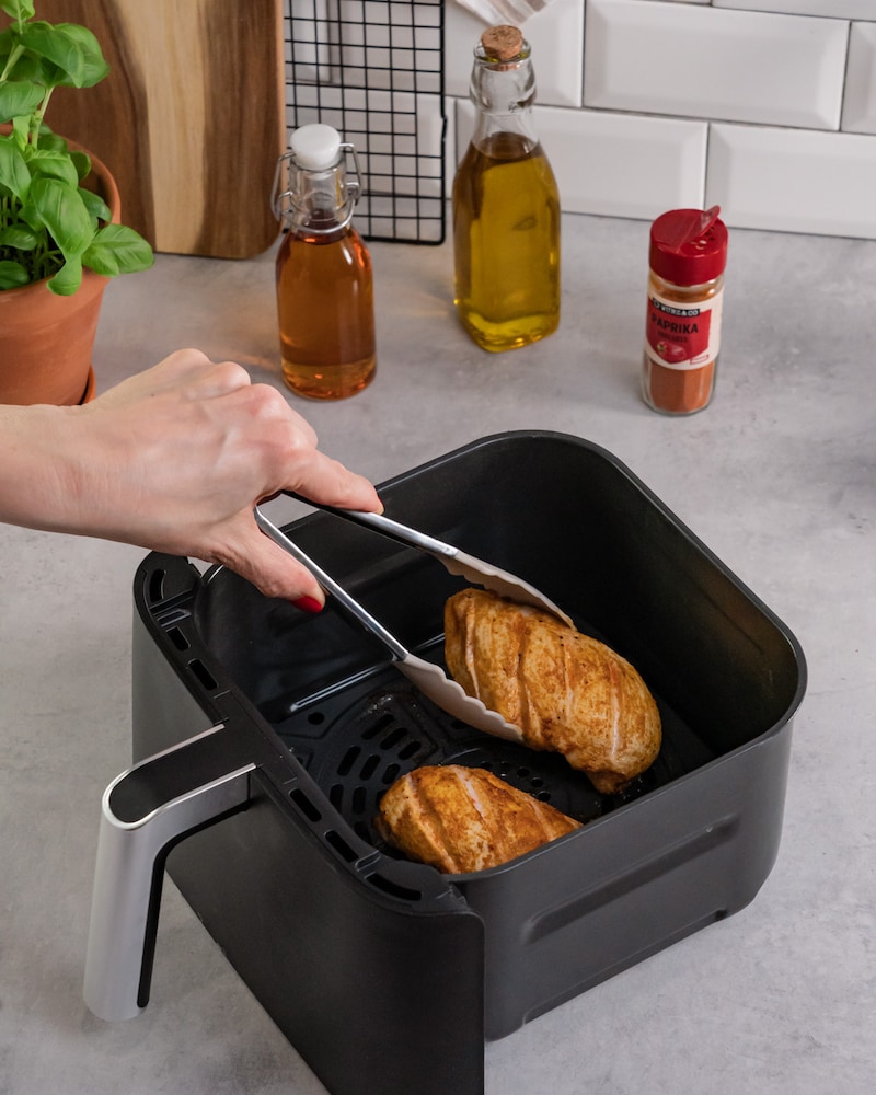 Dieses Bild zeigt, wie die fertige Hähnchenbrust aus der Fritteuse genommen wird.