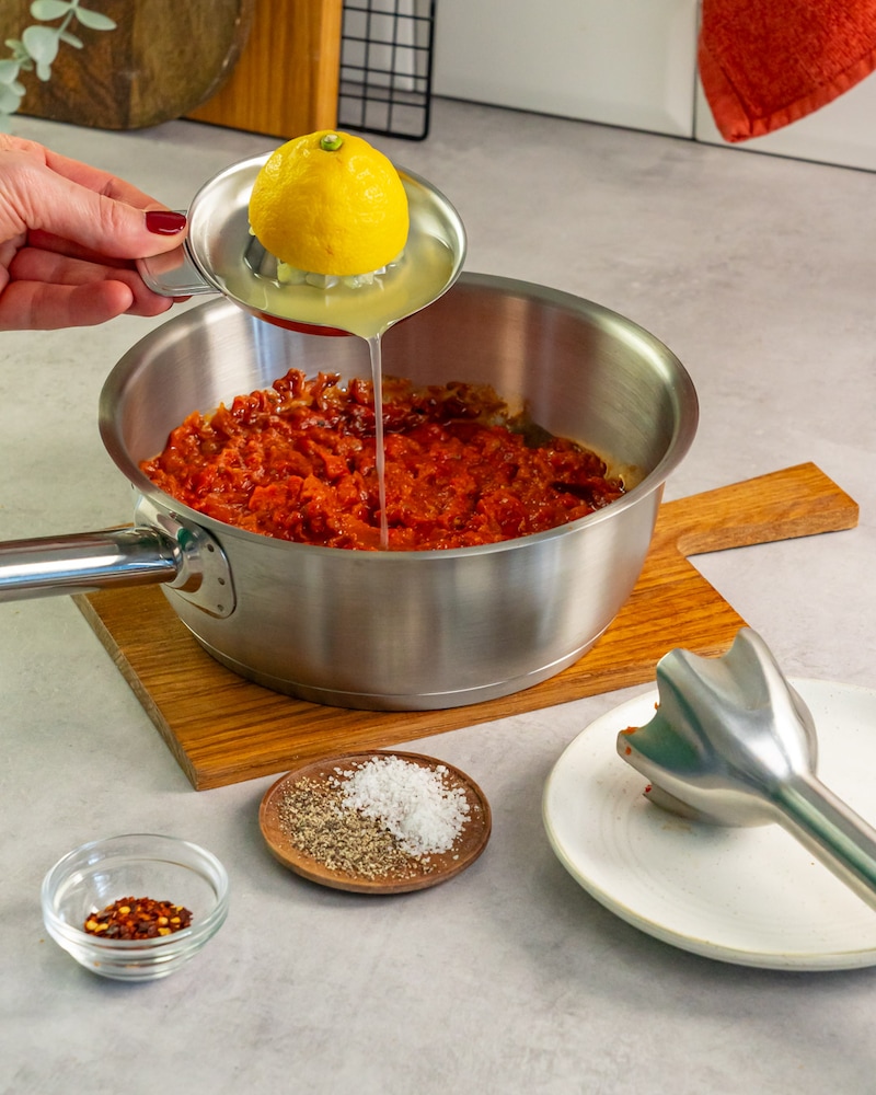 Dieses Bild zeigt wie Zitronensaft zu dem Ajvar dazugegeben wird.
