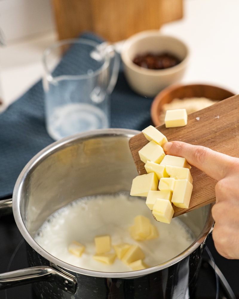 Auf diesem Bild siehst du wie kleine Butterstückchen in Milch erhitzt werden.