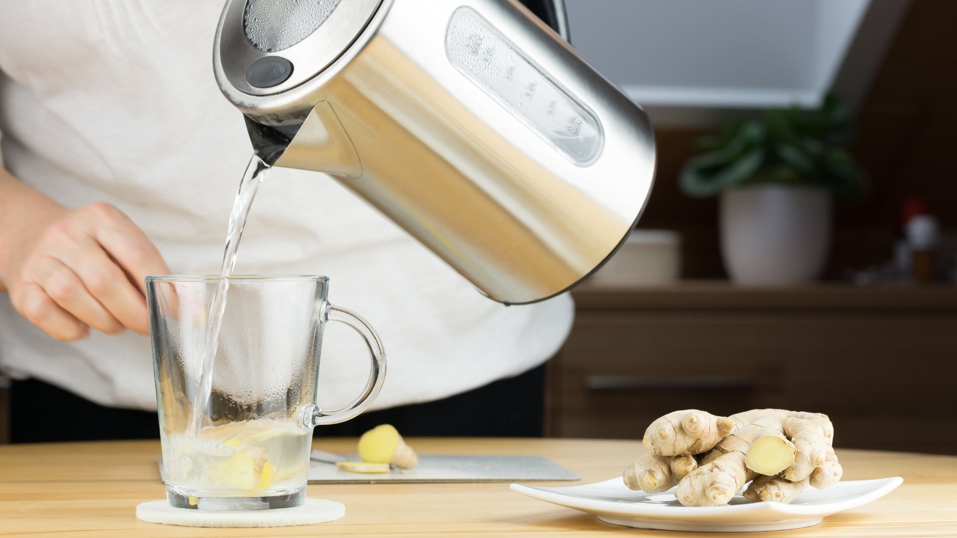 Wasserkocher gießt Wasser auf Ingwer und Zitrone ins Glas