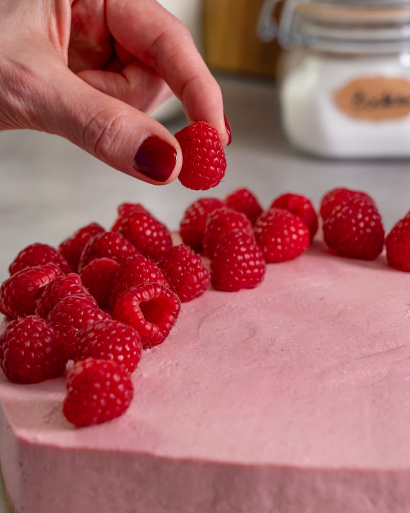 Dieses Bild zeigt wie das Himbeeren auf dem Kuchen verteilt werden.