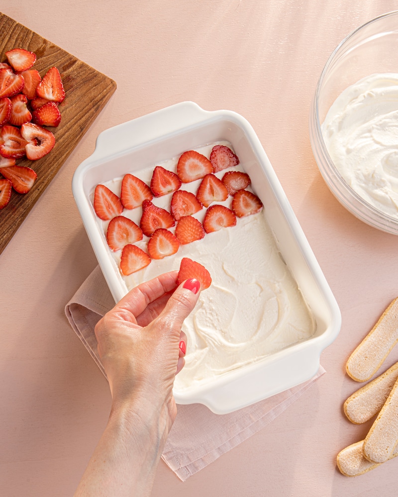 Das Bild zeigt wie das Tiramisu mit Erdbeeren belegt wird.