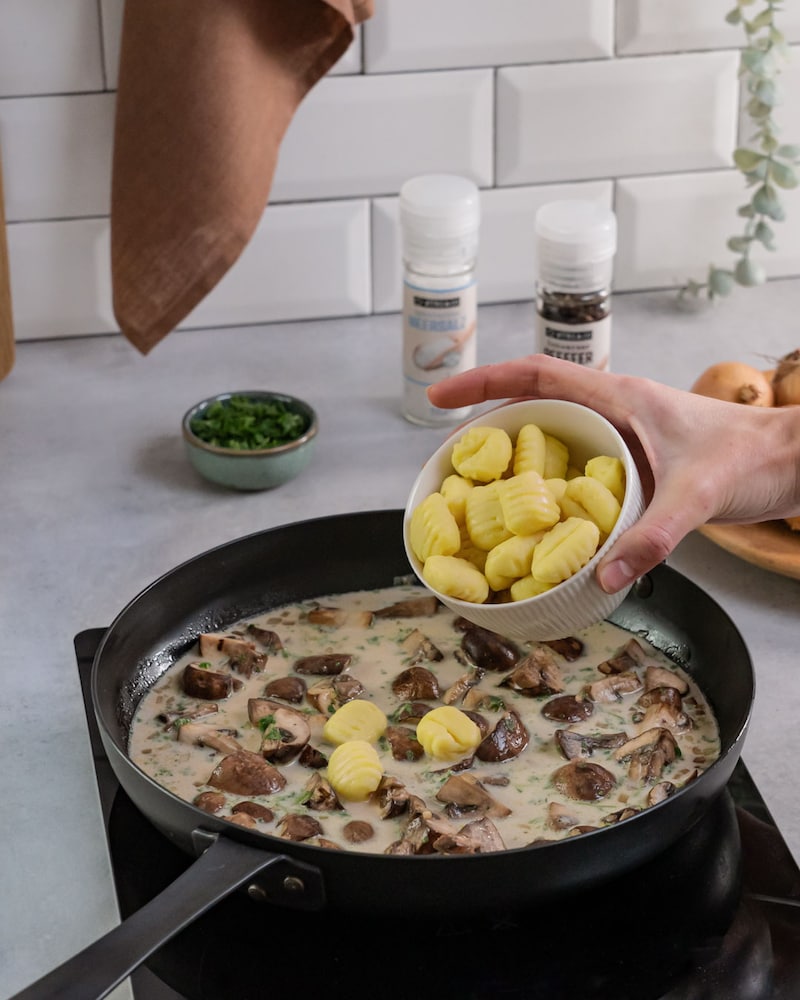 Dieses Bild zeigt wie die Gnocchi zu den Pilzen in die Pfanne gegeben werden.