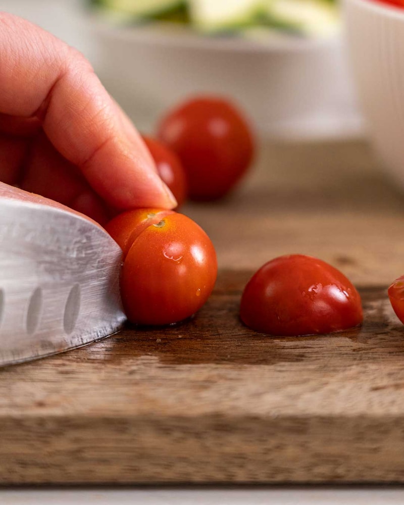 Auf diesem Bild siehst du wie Kirschtomaten geschnitten werden.