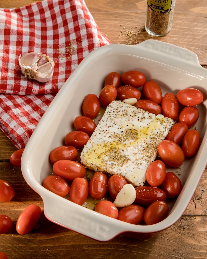 Auf diesem Bild siehst du ein Stück Feta, dass von Kirschtomaten umgeben ist.