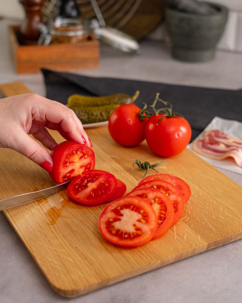 Dieses Bild zeigt wie die Tomaten in Scheiben geschnitten werden.