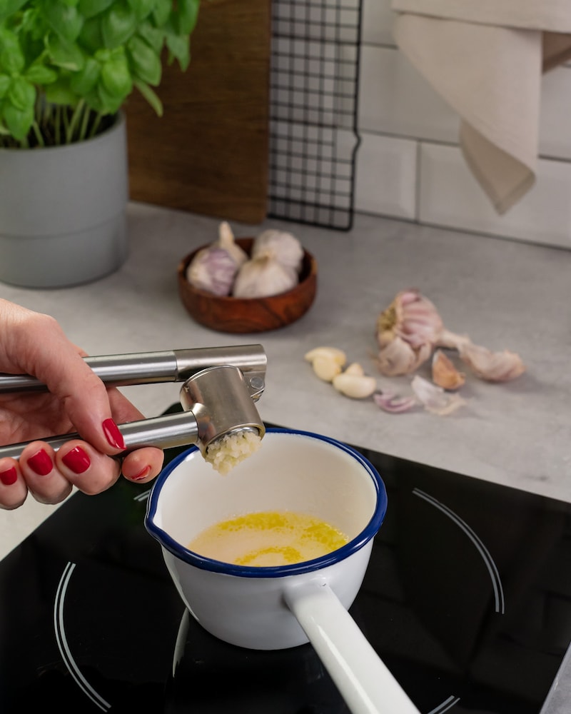 Dieses Bild zeigt wie der Knoblauch in die Butter gepresst wird.