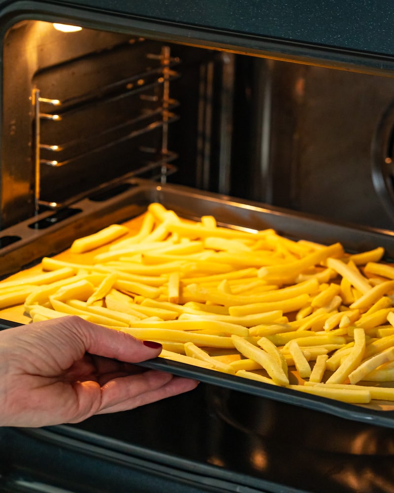 Dieses Bild zeigt wie die Pommes in den Backofen geschoben werden.
