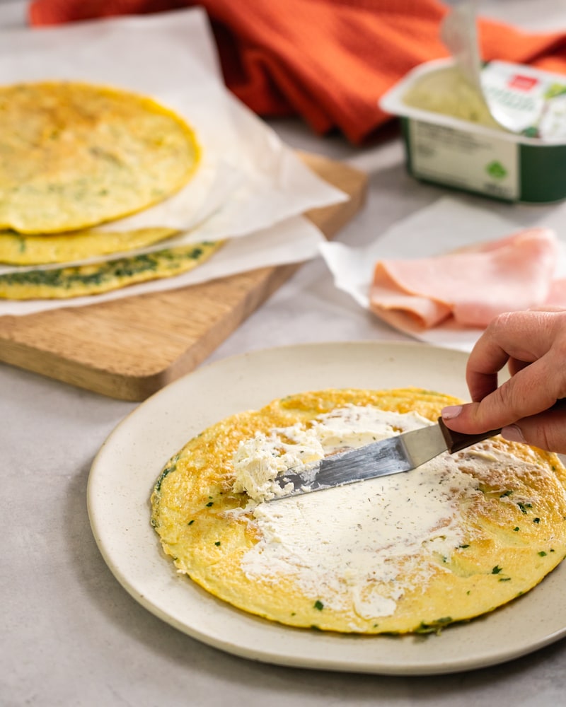 Dieses Bild zeigt wie das Omelett mit Frischkäse bestrichen wird.